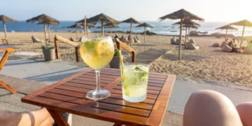 Woman enjoying a Porto tonic cocktail at a beach bar in Porto, Portugal