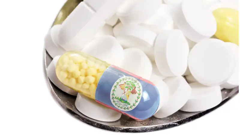 Spoon full of pills and a capsule with the flagdesign of Belize