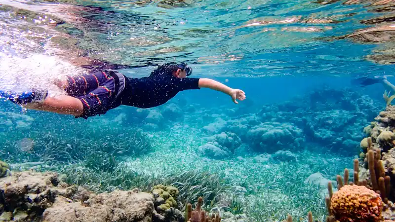 Underwater image of boy snorkeling through coral reef near Ambergris Caye, Belize