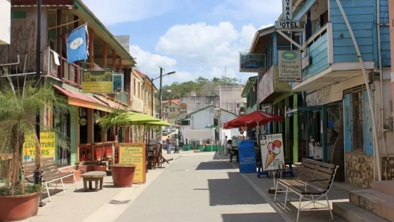 Colorful street scene with shops, signs, and umbrellas in a small tropical town.