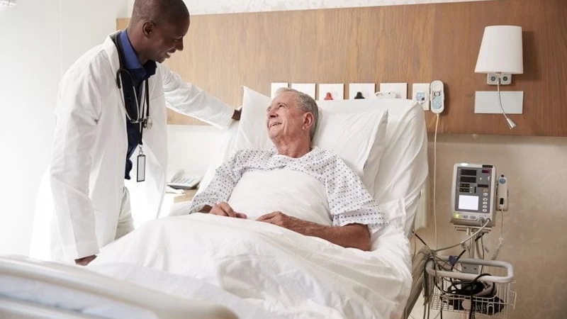 Doctor Visiting And Talking With Senior Male Patient In Hospital Bed. health care in belize