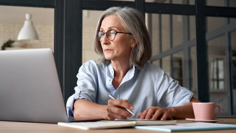 Older woman watching training webinar on laptop working from home