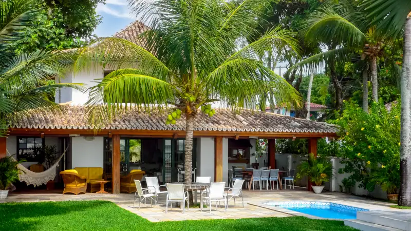 ITAPARICA, BAHIA STATE, BRAZIL: front view of luxury villa, portuguese colonial style, beautiful tropical lawn, palm trees, white walls, terracotta roof tiles, veranda and swimming pool