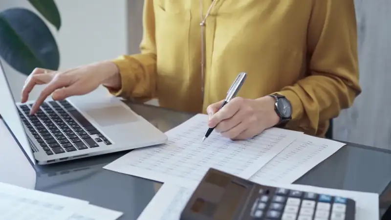 Professional business woman in yellow blouse is working on financial reports. Close-up of a woman's hands as she works on finance documents. Audit and taxes