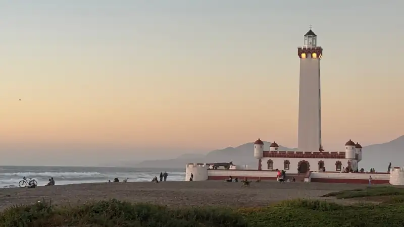 El Faro Monumental in La Serena, Chile, at sunset with beach, waves, and people nearby.