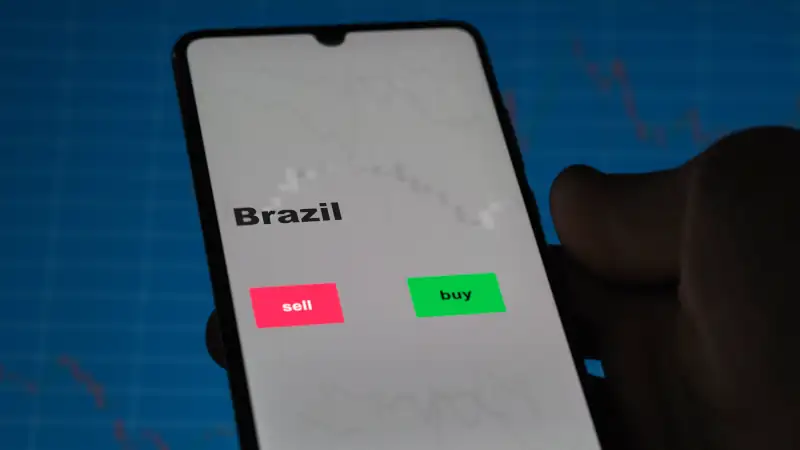 An investor's analyzing the Brazil etf fund on screen. A phone shows the ETF's prices Brazilian brazil brazilian to invest