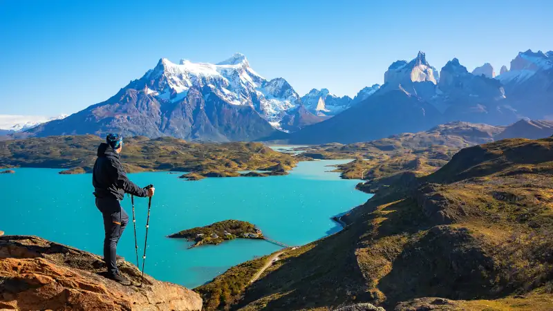 Hiker at mirador condor enjoying amazing view of Los Cuernos rocks and Lake Pehoe in Torres del Paine national park, Patagonia, Chile