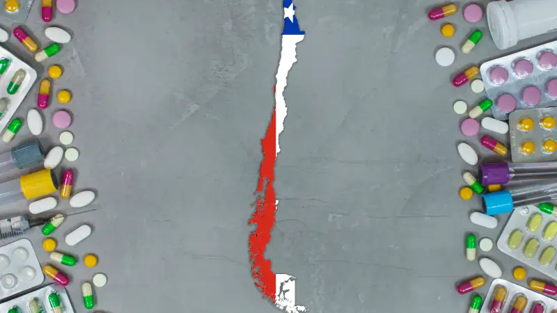 Medicine, pills, needles, syringes and Chile map and flag on gray background.