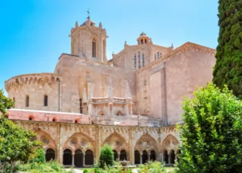 Exterior view of Tarragona Cathedral in Spain, with Gothic architecture and a garden courtyard in the foreground.