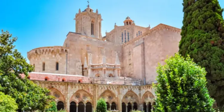 Exterior view of Tarragona Cathedral in Spain, with Gothic architecture and a garden courtyard in the foreground.