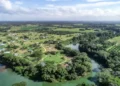 Aerial view of the rural village of Carmelita surrounded by lush greenery and winding rivers in Belize.