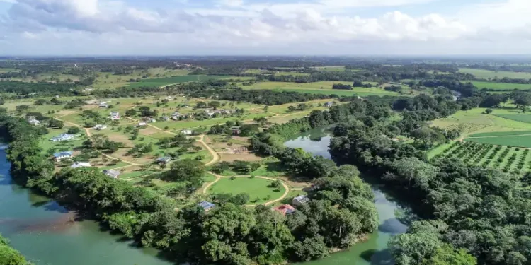 Aerial view of the rural village of Carmelita surrounded by lush greenery and winding rivers in Belize.