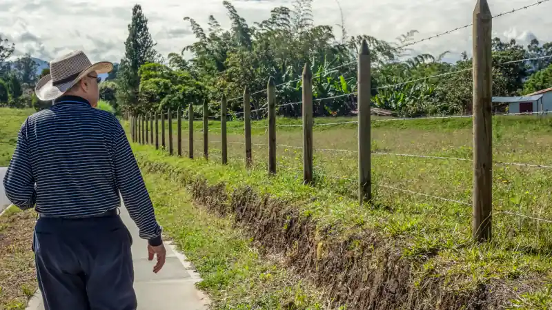 Senior hispanic landowner walking next to his farm in Colombia