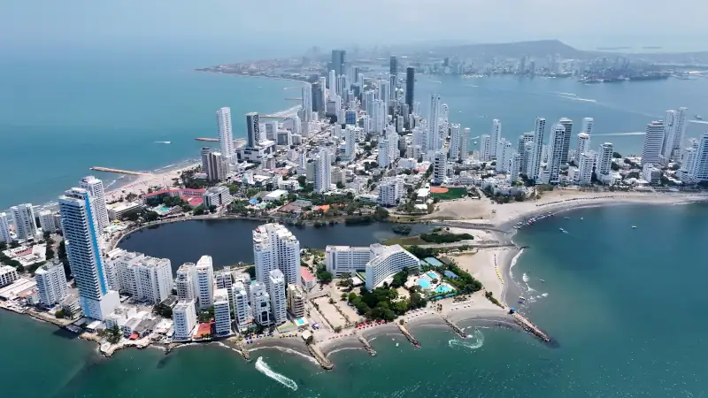 Turquoise Ocean Waves Gently Crashing On Tropical Beach. Business Sky Downtown Cityscape.