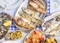 Barbecued sea bass, golden, horse mackerel accompanied with tomato salad, clams, bread and white wine