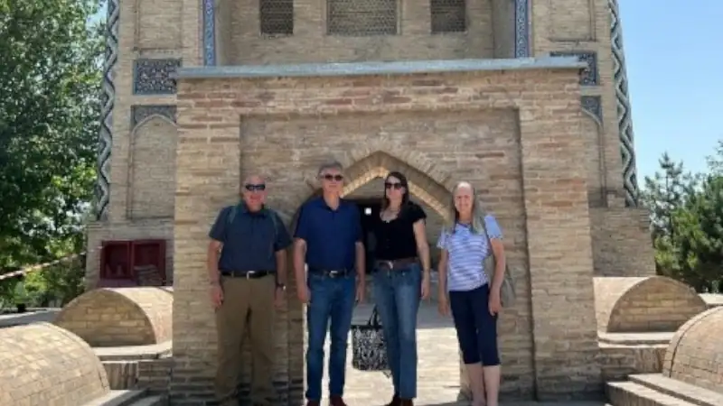 Kathleen, Lief, and two others stand in front of a historic brick building with arched entrances and tilework.
