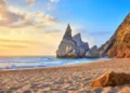 Portugal Ursa Beach at atlantic coast of Atlantic Ocean with rocks and sunset sun waves and foam at sand of coastline picturesque landscape panorama.