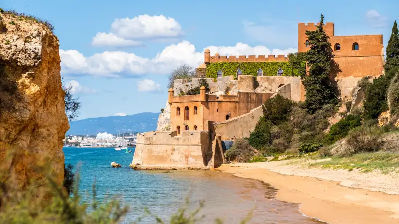 Coastline with sandy beach and castle in Ferragudo, Algarve, Portugal