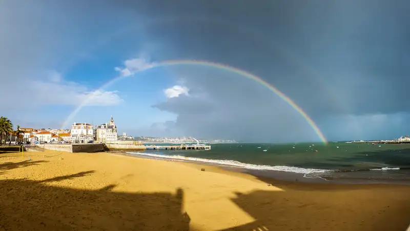 Double rainbow stretching over the beach and waterfront of Cascais, Portugal
