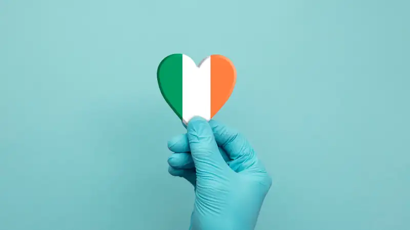 Hands wearing protective surgical gloves holding Ireland flag heart