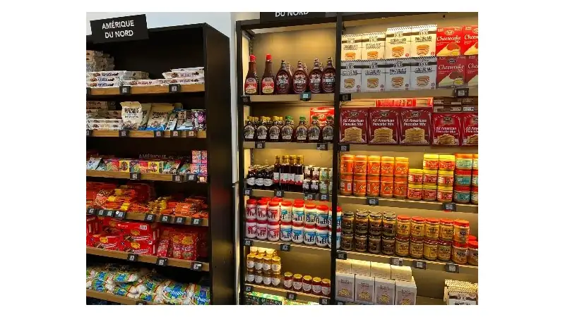 Shelves in a grocery store displaying imported North American foods, including snacks, pancake mixes, syrups, and peanut butter.