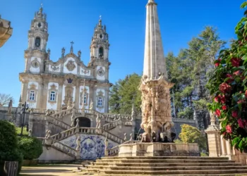Nossa Senhora dos Remédios Sanctuary in Lamego, Portugal, with the church in the background and fountain with obelisk in the foreground, on a blue sky day.