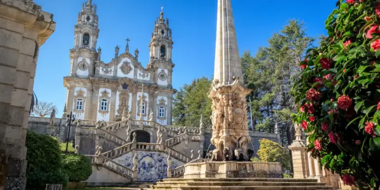 Nossa Senhora dos Remédios Sanctuary in Lamego, Portugal, with the church in the background and fountain with obelisk in the foreground, on a blue sky day.