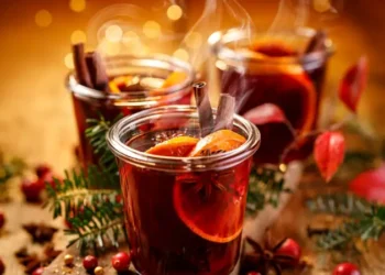 Christmas mulled red wine with aromatic spices and citrus fruits on a wooden rustic table