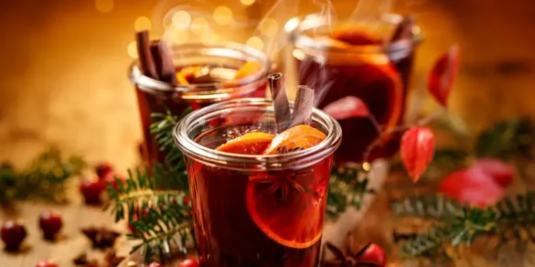 Christmas mulled red wine with aromatic spices and citrus fruits on a wooden rustic table