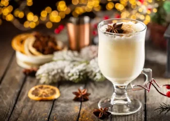 Traditional winter eggnog in a glass mug with milk, rum and cinnamon, christmas decorations
