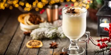 Traditional winter eggnog in a glass mug with milk, rum and cinnamon, christmas decorations