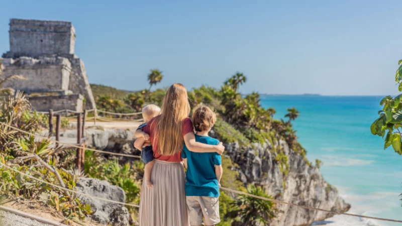 Mother and two sons tourists enjoying the view Pre-Columbian Mayan walled city of Tulum