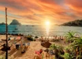 Picturesque view of Cala d'Hort tropical Beach, people hangout in beautiful beach with Es Vedra rock view during magnificent vibrant sunset glowing sun. Balearic Islands, Spain, Espana. Ibiza