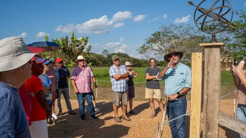 Group of people gathered outdoors at Carmelita Gardens listening to a guide during a tour on a sunny day