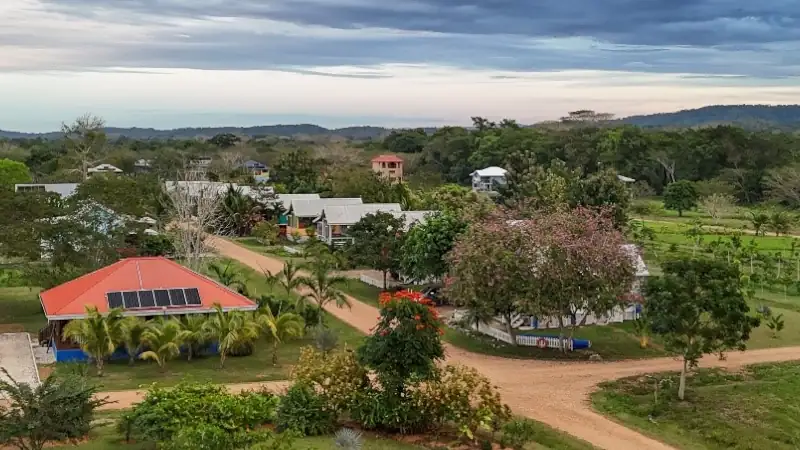 Aerial view of Carmelita Gardens with colorful homes, dirt roads, and lush greenery under a cloudy sky