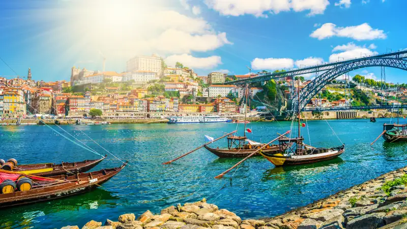 Dom Luis I bridge and traditional boats on Rio Douro river in Porto, Portugal