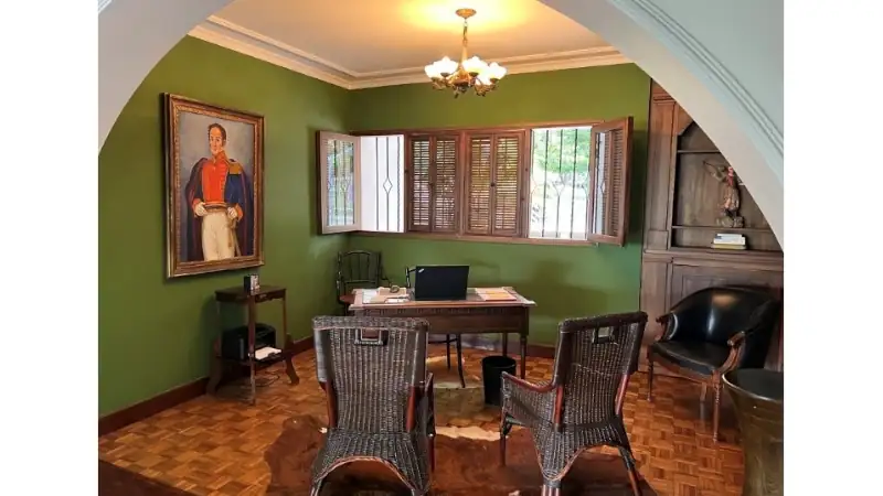 Elegant home office with green walls, wooden floors, and classic furniture decor.