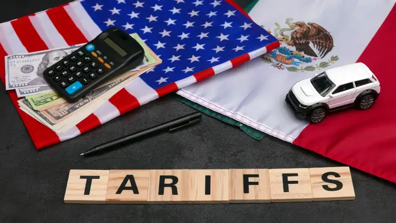 Flags of the USA and Mexico with dollar bills, a calculator, and the text "Tariffs."