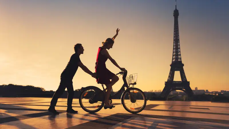 Happy couple riding bicycles in Paris, symbolizing lifestyle and travel