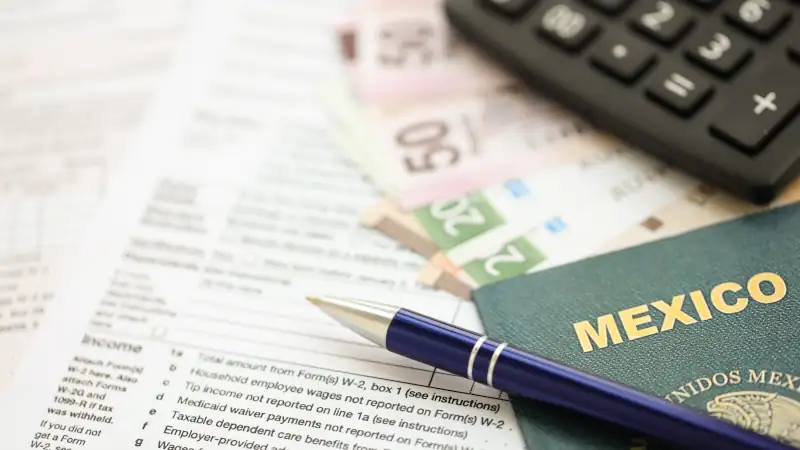 Mexican pesos money bills in big amount lies on table with pen, calculator, passport and tax forms