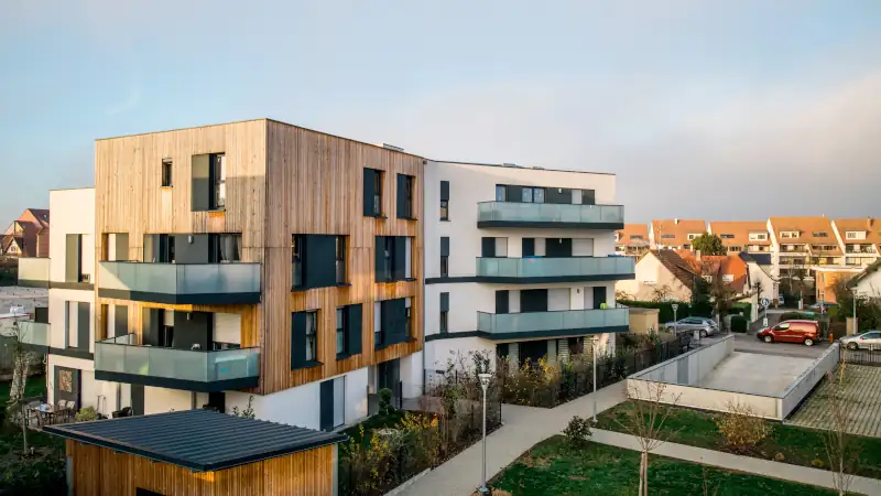 Modern townhouses in a residential area with multiple new apartments buildings surrounded by green outdoor facilities with cars parked on the street