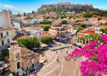 Skyline of Athens with Monastiraki square, Church of Pantanassa and Acropolis hill during summer sunny day. Athens, Greece. Pink bougainvillea flower in the foreground.