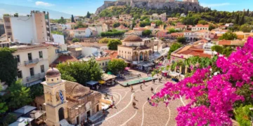 Skyline of Athens with Monastiraki square, Church of Pantanassa and Acropolis hill during summer sunny day. Athens, Greece. Pink bougainvillea flower in the foreground.