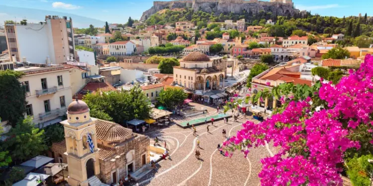 Skyline of Athens with Monastiraki square, Church of Pantanassa and Acropolis hill during summer sunny day. Athens, Greece. Pink bougainvillea flower in the foreground.