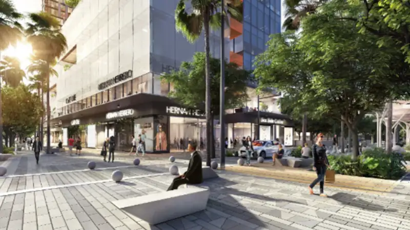 Modern city street with retail shops, pedestrians, palm trees, and contemporary buildings in a lively urban setting.