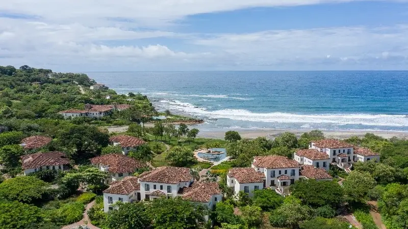 Oceanfront villas with red-tiled roofs surrounded by lush greenery along the Pacific coast at Rancho Santana.