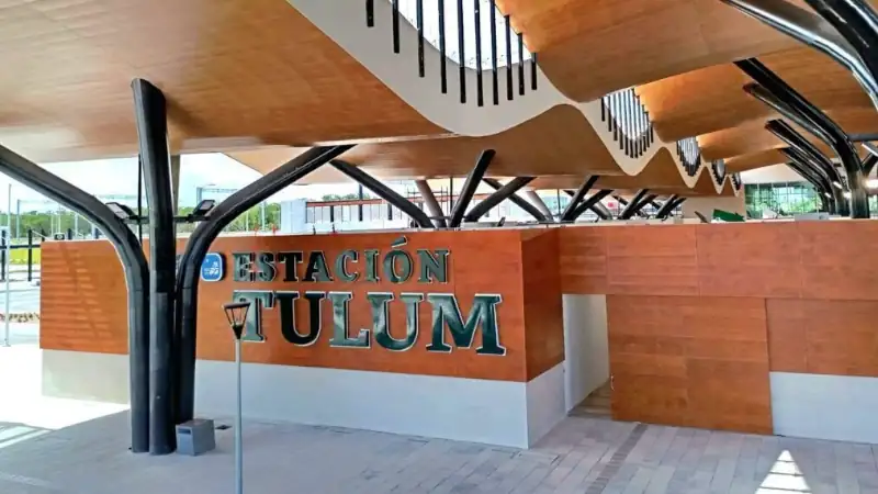 Contemporary entrance of Tulum train station featuring a sleek wooden canopy, curved design elements, and black structural beams.