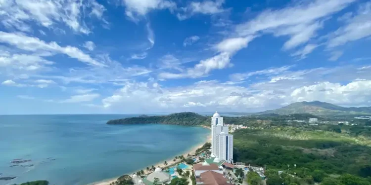 Aerial view of a beachfront resort along Panama’s Pacific coast, with tropical greenery, turquoise waters, and a white luxury tower beside the beach.