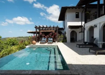 Luxury villa at Los Islotes featuring an infinity pool, covered terrace, and tropical hillside views under a bright blue sky.