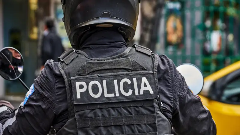 Police officer in black tactical uniform patrolling a street in Vilcabamba.